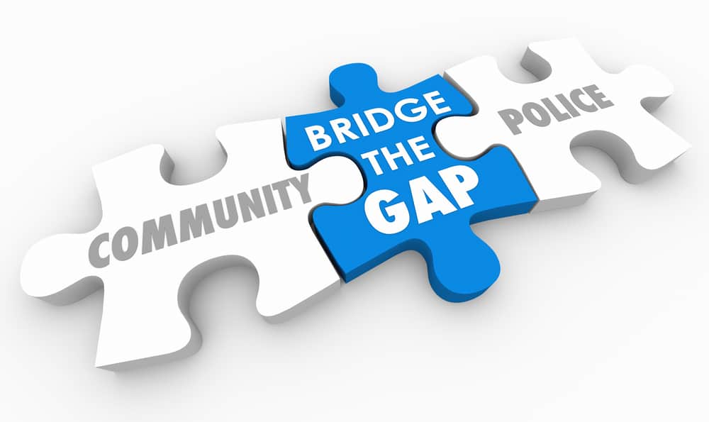 the words community and police shaped as puzzle pieces linked by a bridge the gap puzzle peice